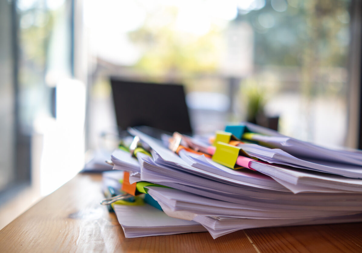 Businesswoman hands working on stacks of paper documents to search and review documents piled on table before sending them to board of directors to use  correct documents in meeting with Businessman